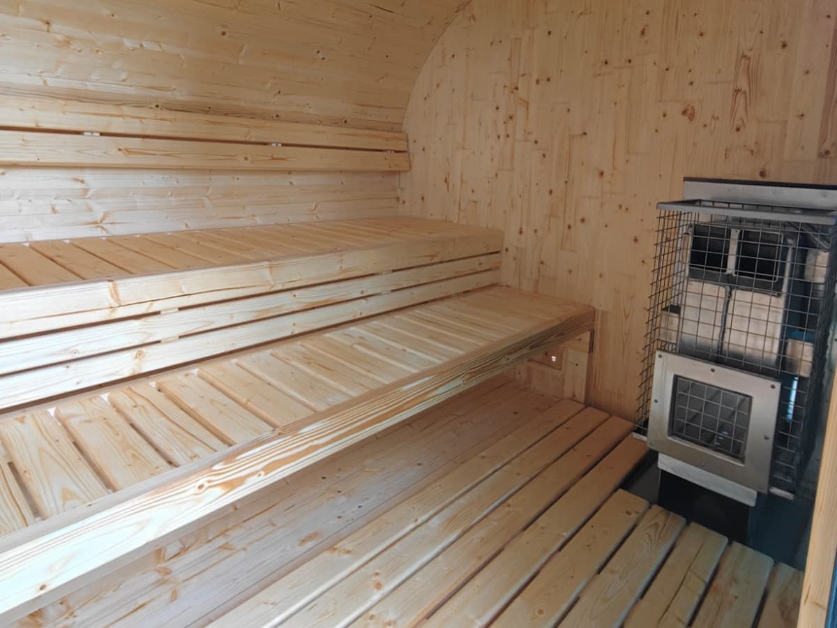 Gartensauna von innen mit Sitzbänken und Ofen