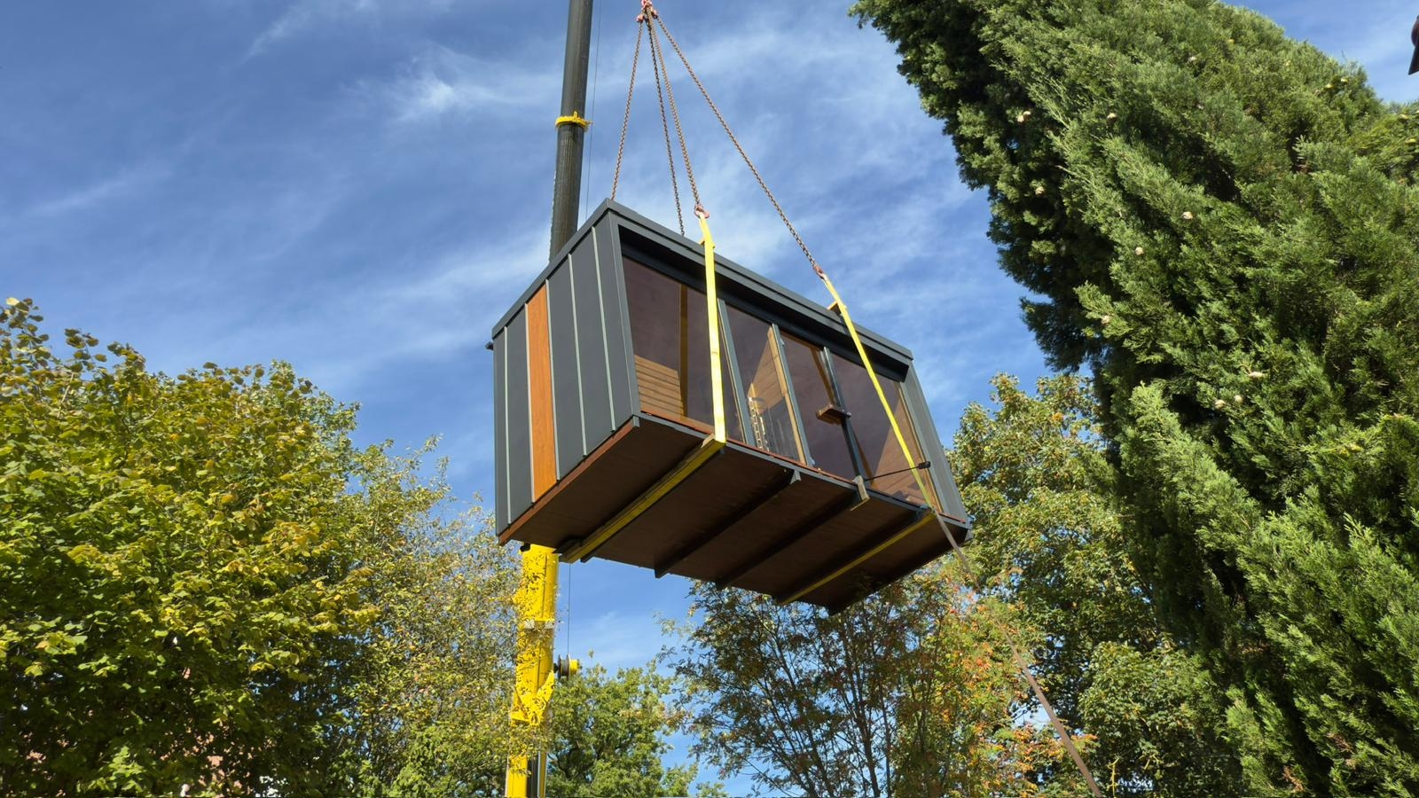Gartensauna wird mit Kran an den Aufstellort gehoben